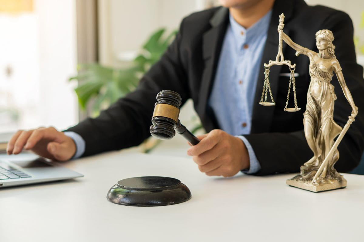 A man in black jacket holding a gavel near table.